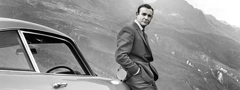 Sean Connery leaning against the classic Aston Martin DB5 used in Goldfinger.