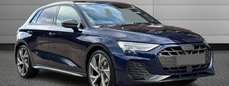 A dark blue Audi A3 parked outside in front of a building.