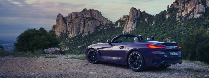 A BMW Z4 parked in a rocky setting at sunset.