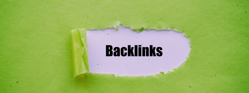 Backlinks text revealed through torn green paper, representing the importance of backlinks in SEO and online visibility.