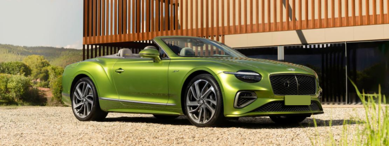 Luxurious green convertible sports car parked outside a modern building on a sunny day, showcasing sleek design and high-end automotive craftsmanship.