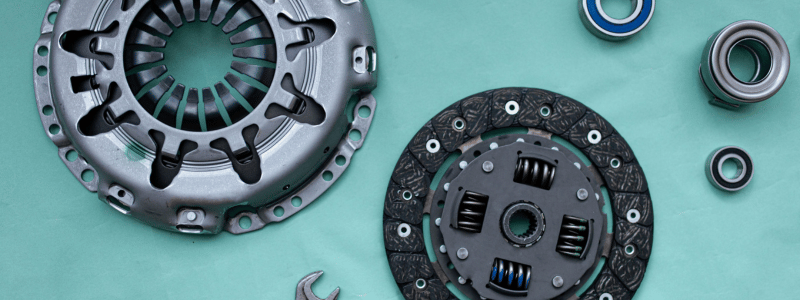 Close-up of car clutch parts and bearings laid out on a green background, symbolising automotive repair, maintenance, and mechanical components.