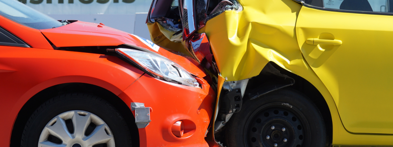 Close-up of a rear-end collision involving a red and a yellow car, showing significant damage to both vehicles.