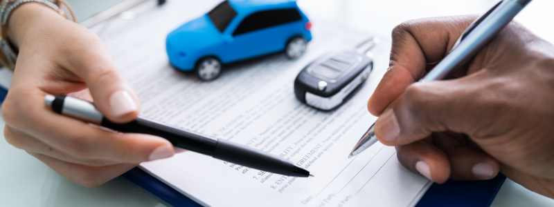 Two hands with pens hover over the signing area of a car-related document.