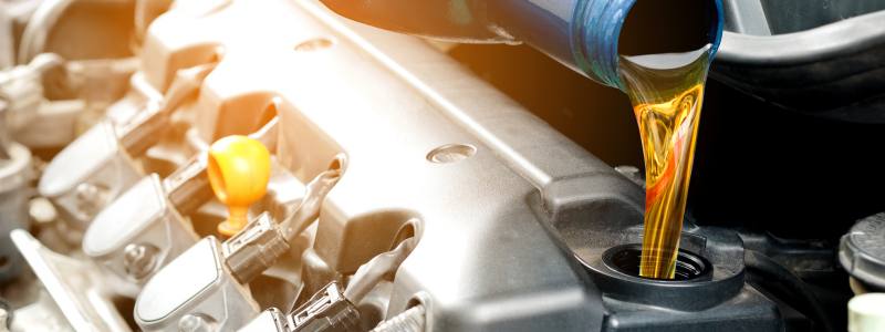 Pouring engine oil into a car's engine during an oil change.