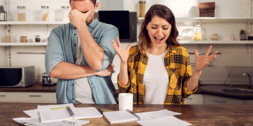 Two people in visible stress whilst looking over documents and papers.