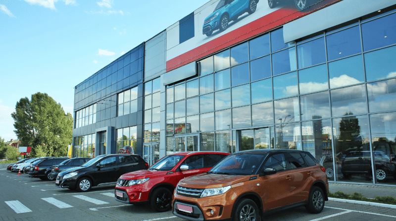 The outside of a car dealership with cars parked outside. 