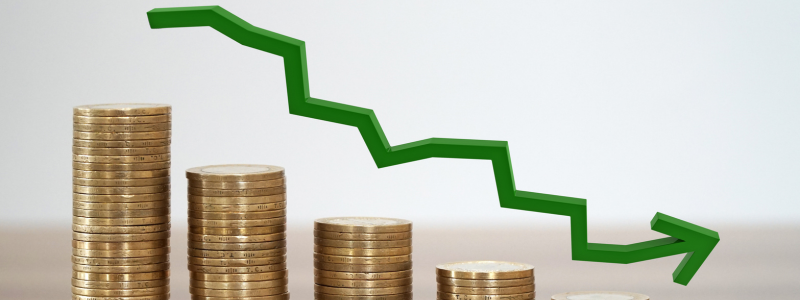 Stacks of coins decreasing in size from left to right accompanied by a downward trending arrow from left to right, representing a downward trend in money.