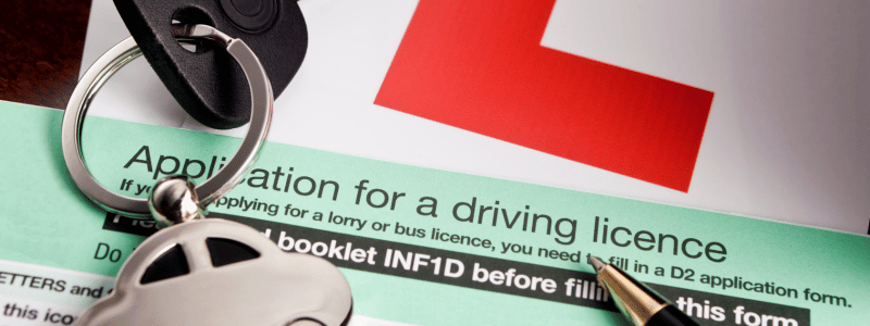 The top of a driving licence application form, with car keys and an L learner plate in shot, representing the journey of becoming a driver.