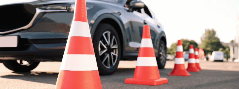 Car manoeuvring around orange traffic cones during a driving test, symbolising precision driving, skill assessment, and road safety training