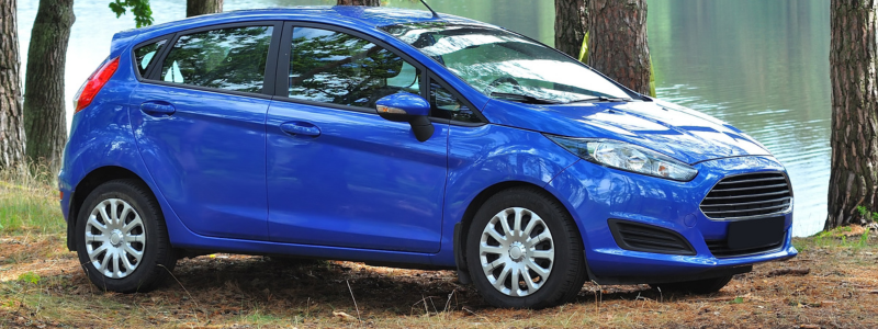 A blue Ford Fiesta parked in a forest setting.