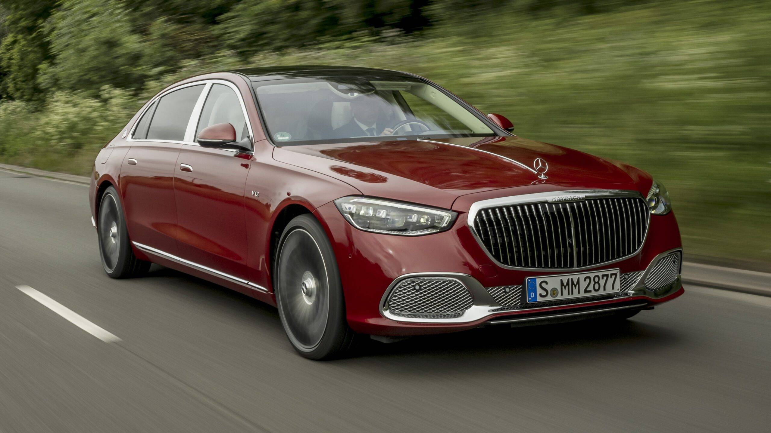 The Mercedes-Maybach S 680 4Matic First Class in dark red, driving on an open road.