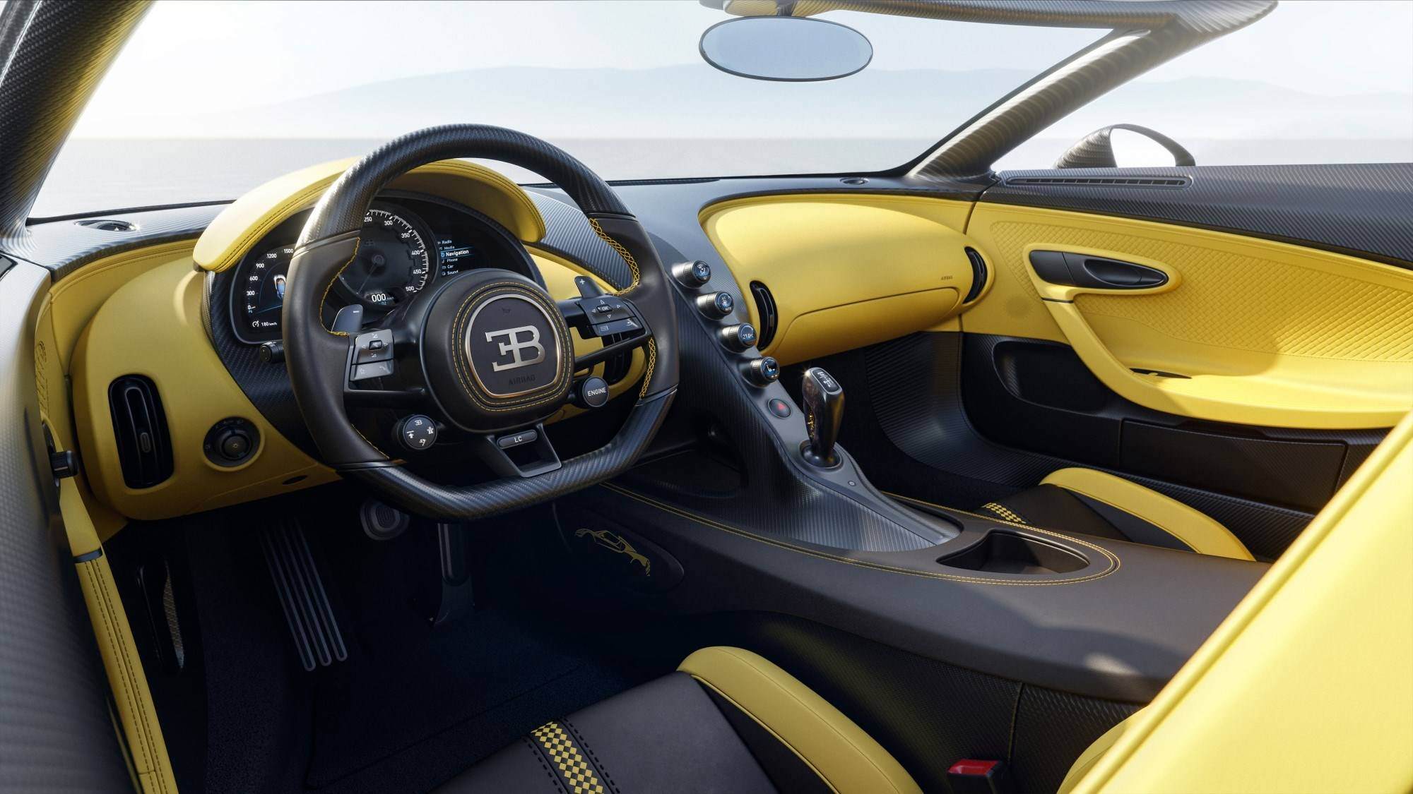 The Bugatti Mistral in black driving on a coastal road with the sea in the background on a sunny day.