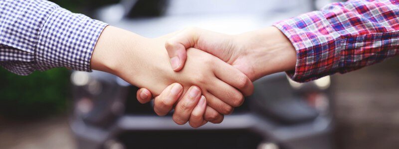 A handshake in front of a car signalling a new deal