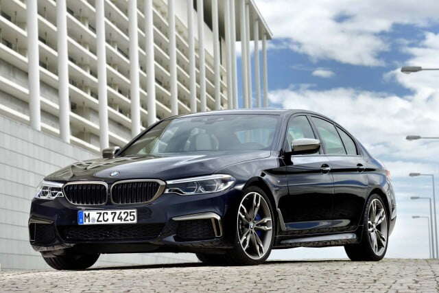 A black BMW 5 Series parked up with a building to the side of it.