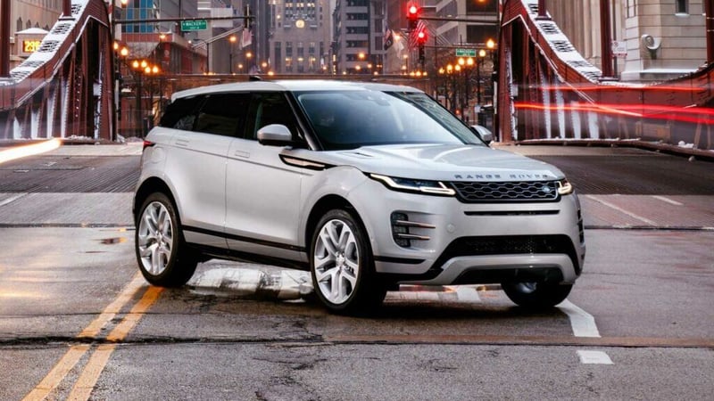 A white Range Rover Evoque parked in front of a bridge.