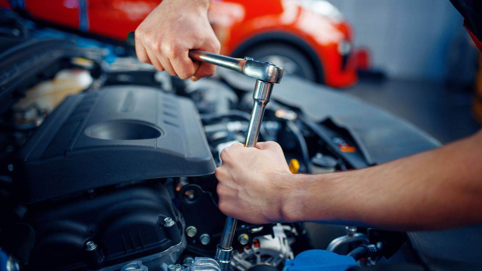 A photo of a male mechanic doing a car service under the bonnet