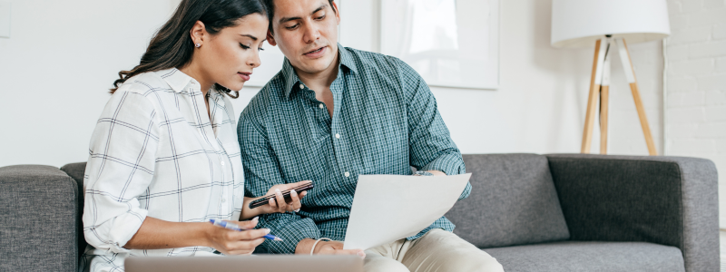 A couple working together whilst looking at a document and writing stuff down, symbolising a partnership and working something out.