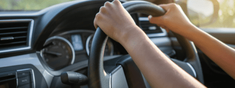 A close-up of hands on a steering wheel.