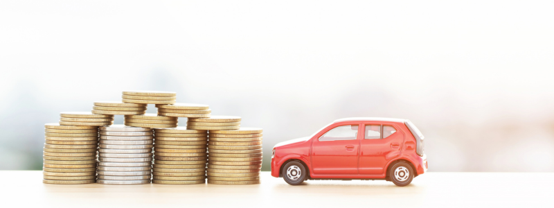 A toy car next to stacks of coins against a light background.