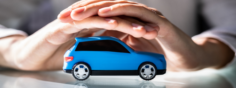 A toy car with two hands over the top of it shielding it.