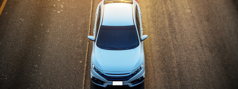 An overhead view of a white car on a road.