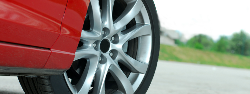 A close up of a car tyre on a red car. 