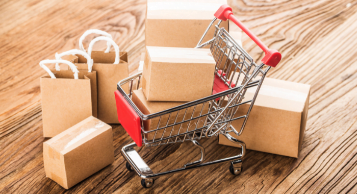 An above shot image of a trolly with cardboard present boxes in. The cart is surrounded by cardboard shopping bags. All of this sits on a light coloured wooden floor.