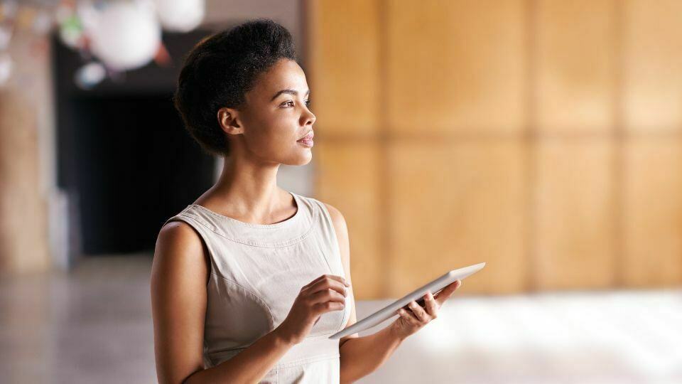 A person looks up from their tablet in contemplation.