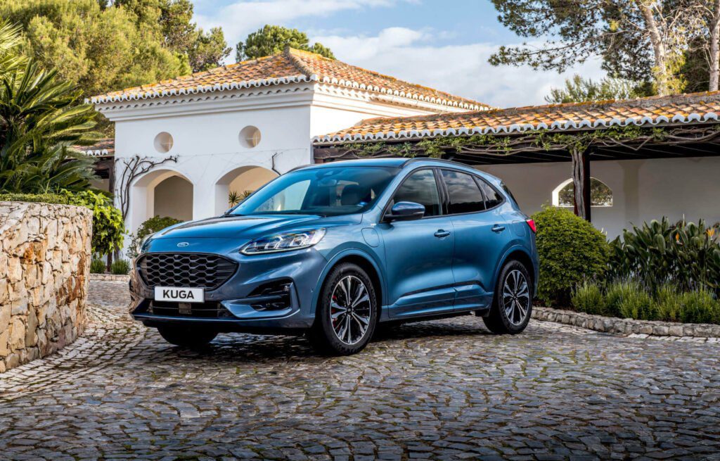 A blue Ford Kuga outside a rural villa, with sun shining down on it, likely as part of a launch photoshoot for the new Ford Kuga.