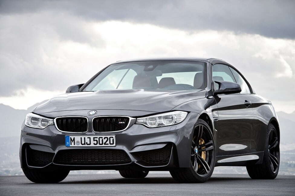 A grey BMW M4 parked below grey clouds.