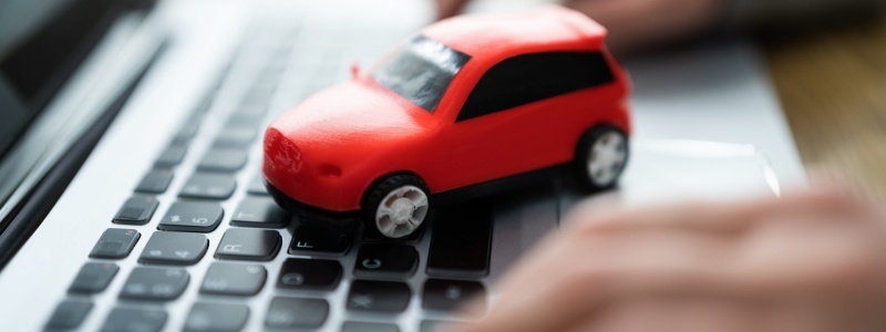 A red toy car sat on a keyboard, symbolising online car buying.