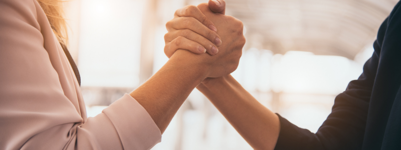 Two people engaged in a firm handshake, indicating a professional agreement, partnership, or greeting.