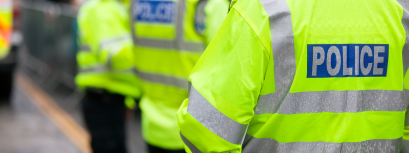 Police officers with their jackets in sharp focus displaying 'police'.