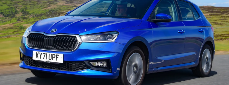 A blue Skoda Fabia driving on a road.