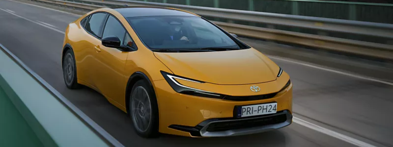 A yellow Toyota Prius driving on a road.