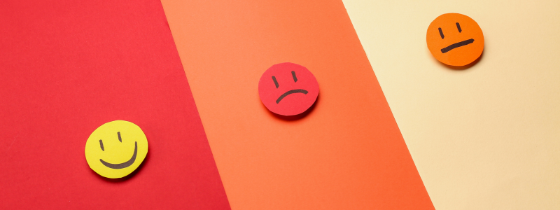 User experience illustration with three faces: happy on yellow, sad on red, and neutral on beige backgrounds, representing different emotions.