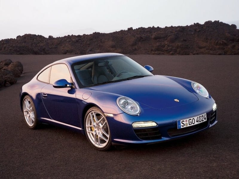 A blue Porsche Carrera S parked up in a rocky area.