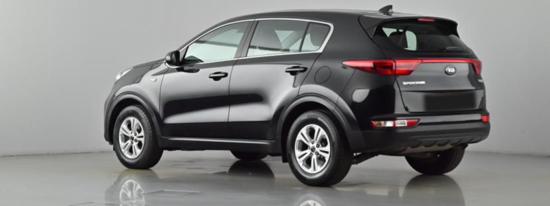 A black Kia Sportage parked side-on against a grey background, likely in a car showroom.