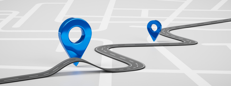 Representation of navigation with a curved road connecting two blue location pins on a simplified map background, symbolising journey and destination.