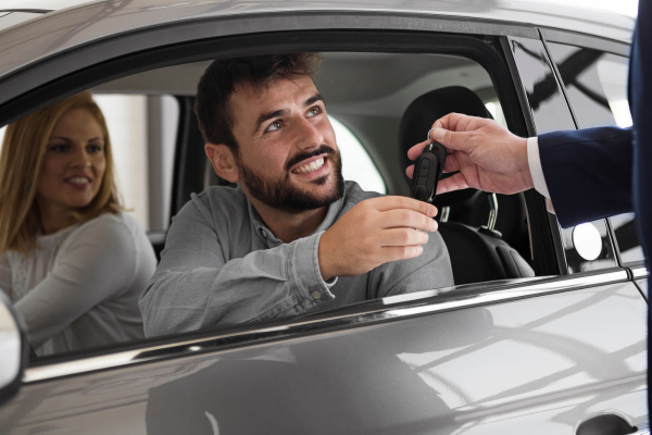 A person takes a key off someone whilst sat in his car with a woman next to him.