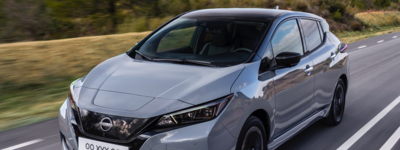 A grey Nissan Leaf driving on a road.