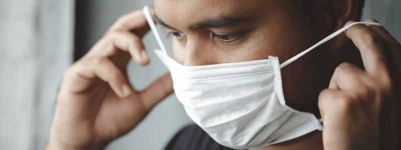 A person applying a face mask, symbolising the Covid-19 pandemic.