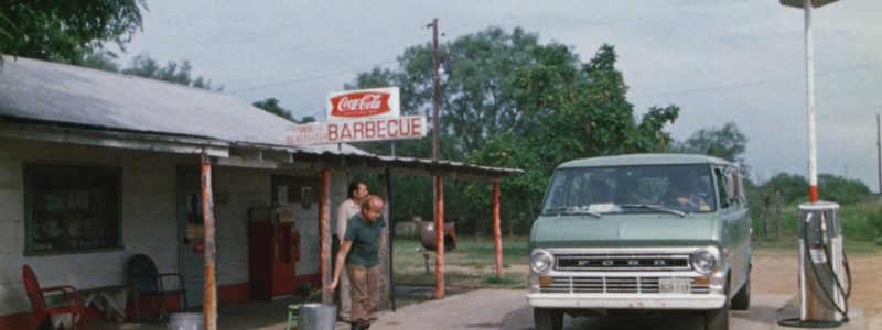 A van parked in front of a garage, as part of the film the Texas Chainsaw Massacre.