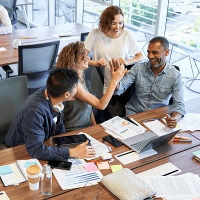 A happy working team in casual dress celebrate an achievement together in a workplace setting.