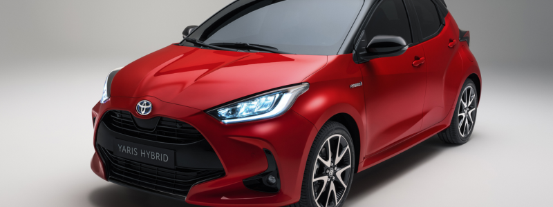 A red Toyota Yaris parked against a blank background.