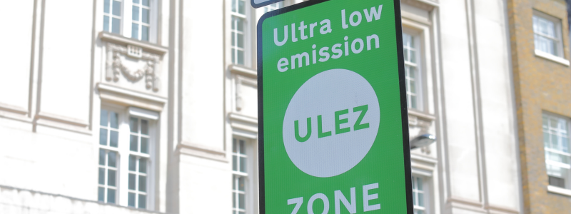 A green ULEZ zone sign in display in a city centre.