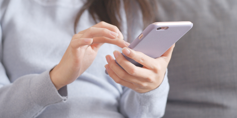 A person in a grey jumper interacting with their phone, representing technology and our relationship with it. 