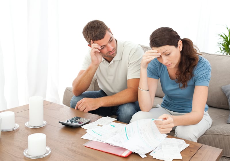 Worried couple doing their accounts in the living room at home.